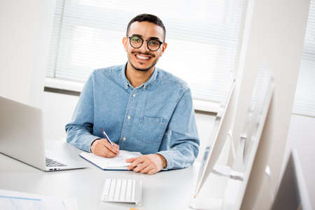Happy handsome arab businessman smiling while looking at camera in officeの写真素材