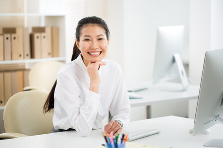 Asian business woman smiling at camera at workplace in an officeの写真素材