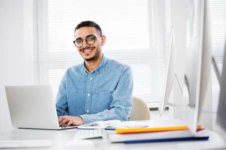 Happy handsome arab businessman smiling while looking at camera in officeの写真素材