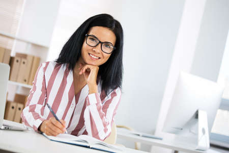 Portrait of a pretty business woman woman with glasses at workplace in officeの写真素材