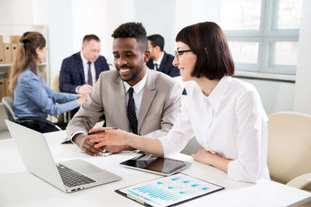 Multy-ethnic group of business people sitting at the office desk and working with computerの写真素材