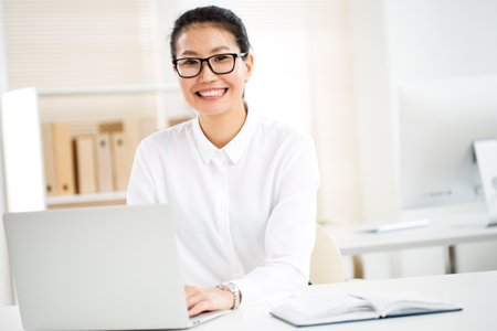 Asian business woman smiling at camera at workplace in an officeの写真素材