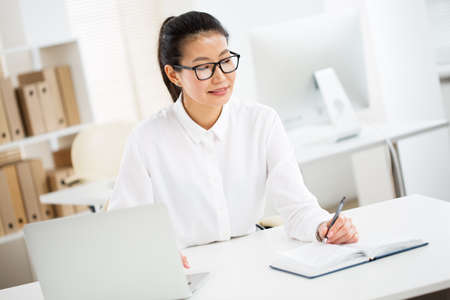 Portrait of a pretty asian business woman at workplace in officeの写真素材