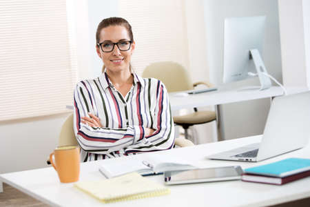 Portrait of a pretty business woman woman with glasses at workplace in officeの写真素材