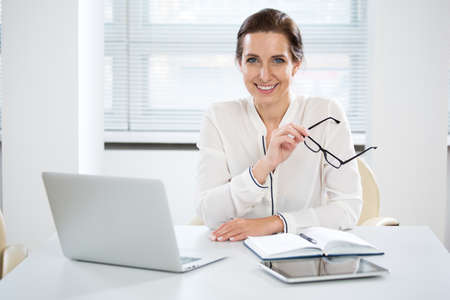 Portrait of pretty business woman looking at camera at workplace in an officeの写真素材