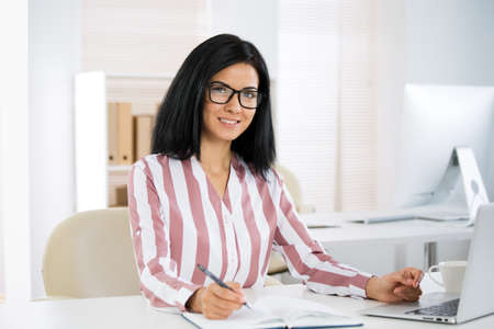 Portrait of a pretty business woman woman with glasses at workplace in officeの写真素材