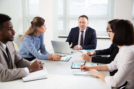 Group of business people sitting around the office desk and discussing the project togetherの写真素材