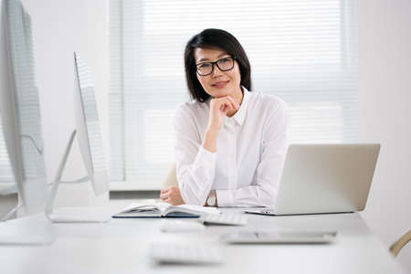 Asian business woman smiling at camera at workplace in an officeの写真素材