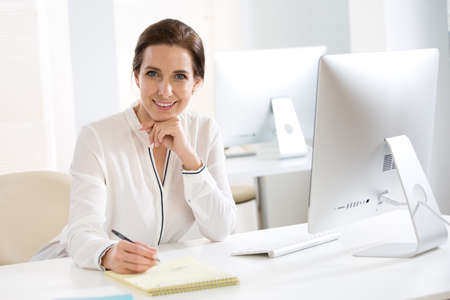 Portrait of pretty business woman looking at camera at workplace in an officeの写真素材