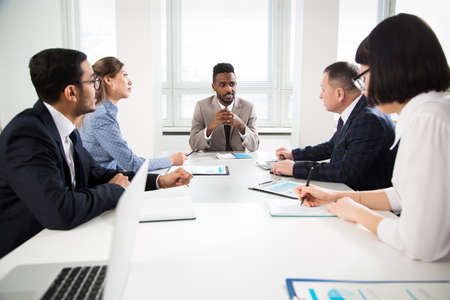 Group of business people sitting around the office desk and discussing the project togetherの写真素材