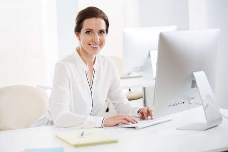 Portrait of pretty business woman looking at camera at workplace in an officeの写真素材