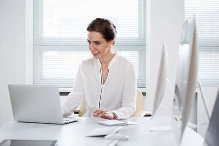 A pretty business woman working alone in an empty officeの写真素材