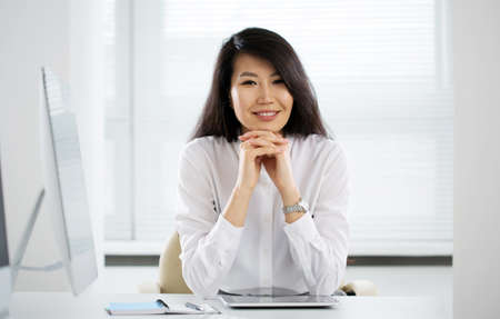 Asian business woman smiling at camera at workplace in an officeの写真素材