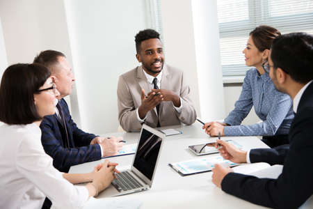 Group of multi-ethnic business people sitting around the office desk and discussing the project togetherの写真素材