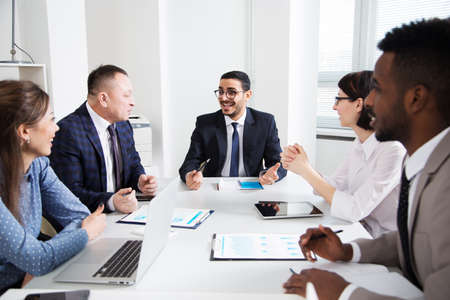 Group of multi-ethnic business people sitting around the office desk and discussing the project togetherの写真素材