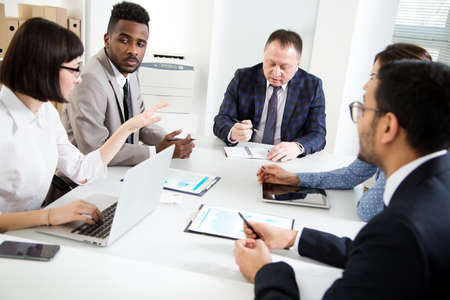 Group of multi-ethnic business people sitting around the office desk and discussing the project togetherの写真素材
