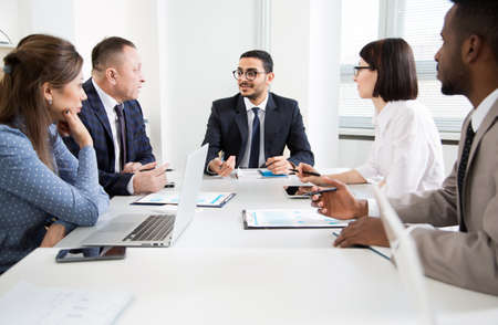 Group of business people sitting around the office desk and discussing the project togetherの写真素材