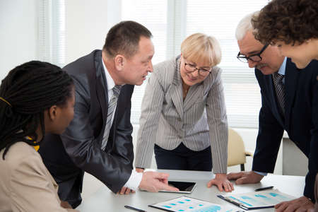 Senior businessman explains to colleague a new project in the modern officeの写真素材
