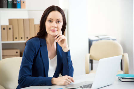 Portrait of pretty business woman looking at camera at workplace in an officeの写真素材
