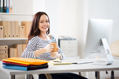 Portrait of pretty business woman looking at camera at workplace in an officeの写真素材