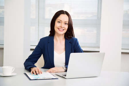 Portrait of pretty business woman looking at camera at workplace in an officeの写真素材