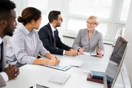 Mature businesswoman explains to colleague a new project in the modern officeの写真素材