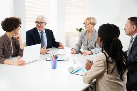 Group of multi-ethnic business people sitting around the office desk and discussing the project togetherの写真素材