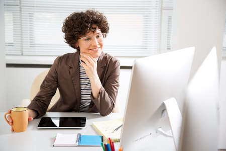 Portrait of a pretty business woman with glasses at workplace in officeの写真素材