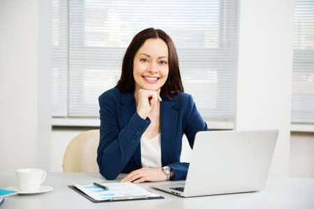 Portrait of pretty business woman looking at camera at workplace in an officeの写真素材