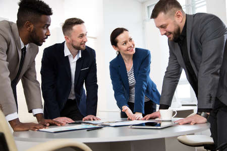 Group of multi-ethnic business people standing around the office desk and discussing the project togetherの写真素材