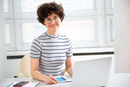 Portrait of pretty business woman looking at camera at workplace in an officeの写真素材