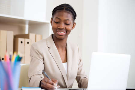 Portrait of pretty african-american business woman working with laptop in an officeの写真素材