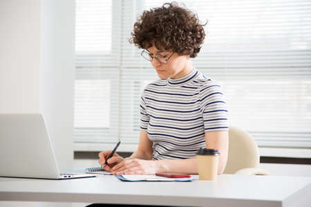 Portrait of a pretty business woman with glasses at workplace in officeの写真素材