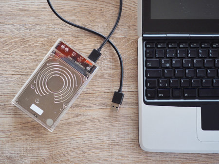 The drive is connected to a notebook computer on a wooden desk. With the concept of keeping...
