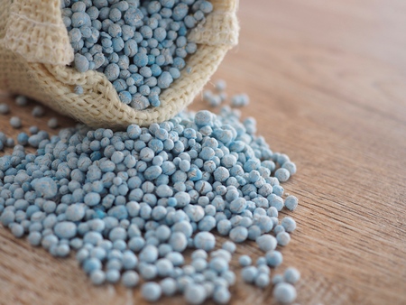 Old chemical fertilizer until the pellets start to break in the sack on the old wood board.の写真素材