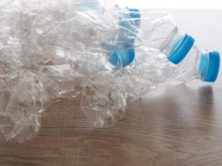 Plastic drinking water bottle Twisted on the wood table before dropping it to the trash. To reduce...