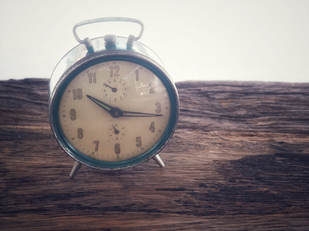 Old winding clock on wooden board In vintage color schemes with the concept of time and memory.