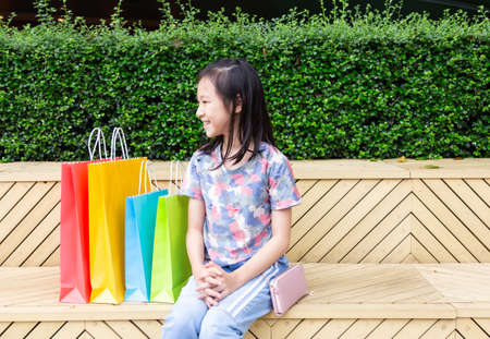 Asian girl sitting outdoor with shopping bagsの写真素材