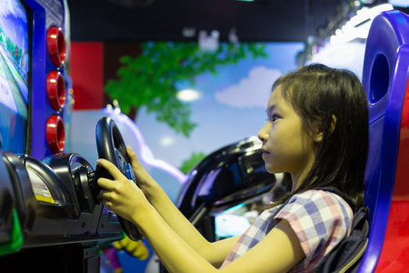 Asian girl playing the car racing game machine at one of the shopping mall outlets