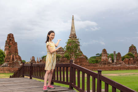 Cute happy smiling tourist girl,relaxing enjoying travelling at Wat Mahathat is a Buddhist temple in the city of Ayutthaya Historical Park,Thailand, summer vacation,travel concept.の写真素材