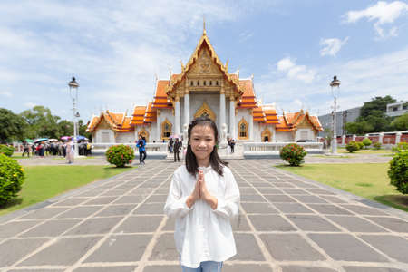 Happy smiling tourist girl,Asian cute girl with pay respect at Wat Benchamabopitr or Marble Temple is a Buddhist temple in the city of Bangkok,Thailand, summer vacation,travel concept.