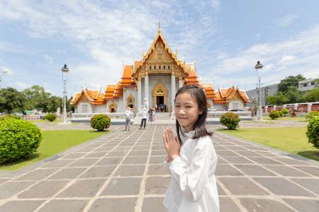 Happy smiling tourist girl,Asian cute girl with pay respect at Wat Benchamabopitr or Marble Temple is a Buddhist temple in the city of Bangkok,Thailand, summer vacation,travel concept.の写真素材