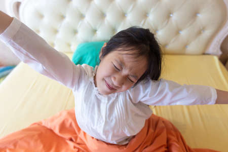 Beautiful girl waking up in her bed,Asian girl smiling and stretching,healthy lifestyle,wellness conceptの写真素材