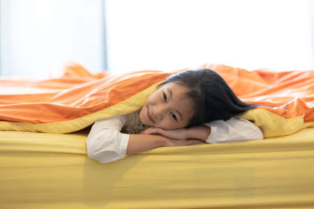 Portrait of little girl under blanket in the bedroom at home,child and home conceptの写真素材