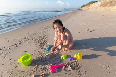 Asian cute girl playing sand on the beach, summer vacation and relax conceptの写真素材