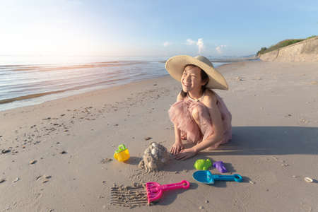 Asian cute girl playing sand on the beach, summer vacation and relax conceptの写真素材