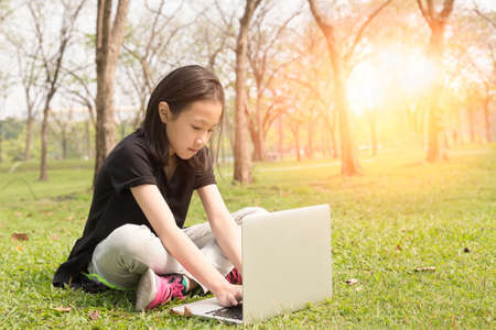 Asian girl is using a laptop in the parkの写真素材