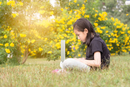 Asian girl is using a laptop in the gardenの写真素材