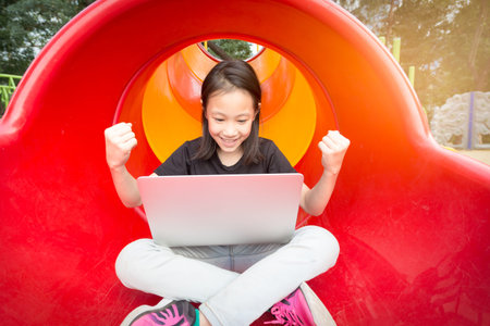 Asian girl is using a laptop in the playgroundの写真素材