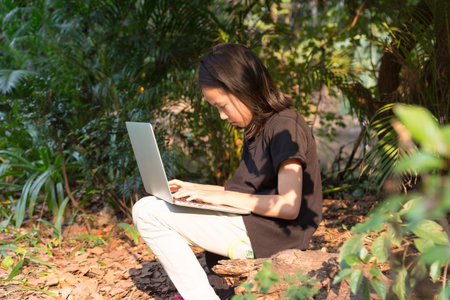 Asian girl is using a laptop in the parkの写真素材